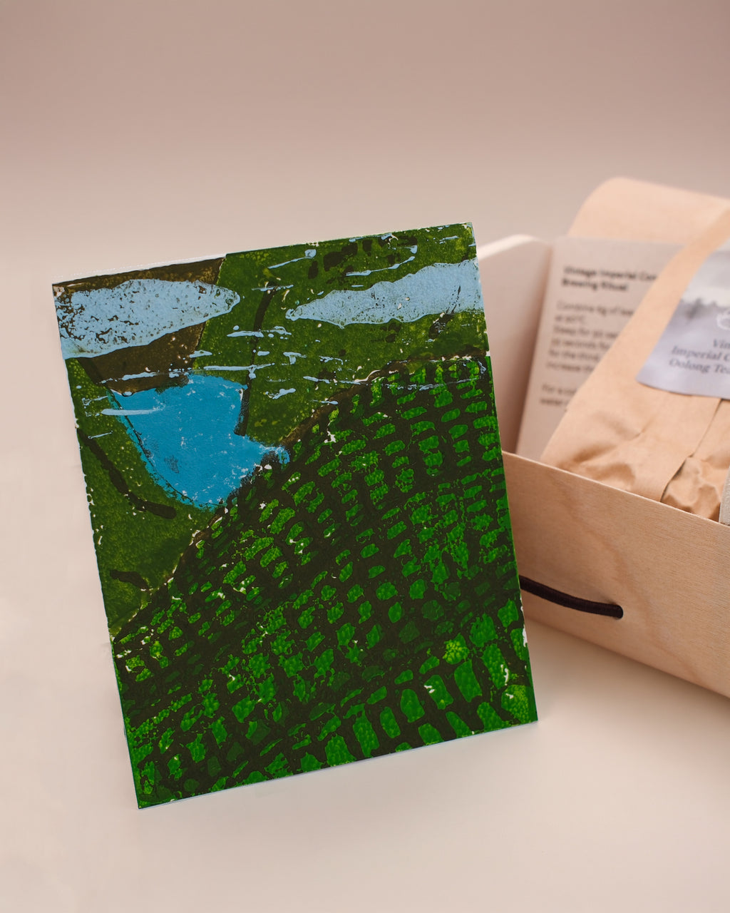 A tea gift box, featuring a linocut postcard in the design of tea fields. This is the 'Vintage Imperial Concubine Oolong Tea (2016)' from Cha Cha Chan.