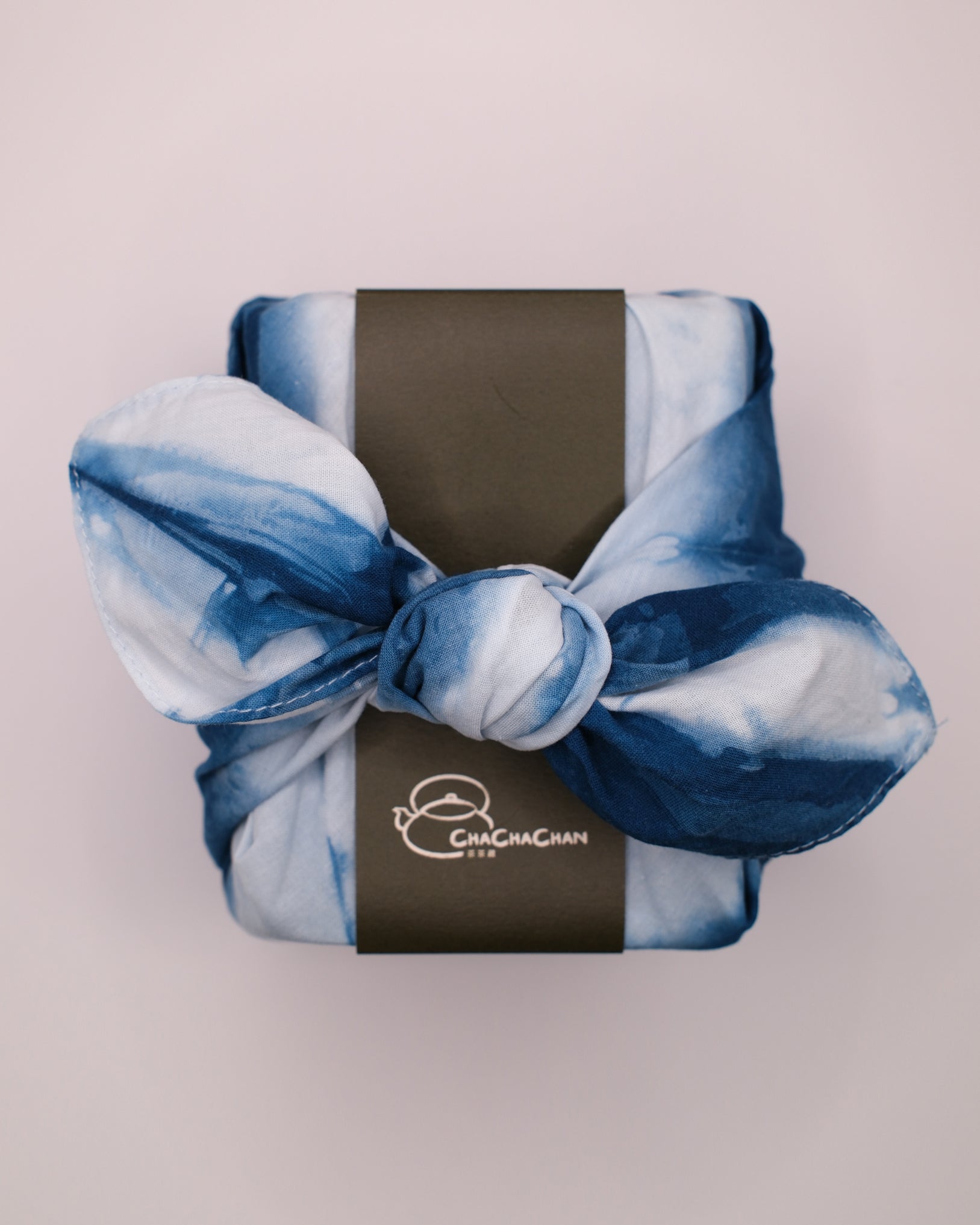 A wrapped tea gift box tied with a blue and white tie-dye furokshiki cloth, featuring a dark brown paper band labelled 'Vintage Imperial Concubine Oolong Tea (2016)' from Cha Cha Chan.