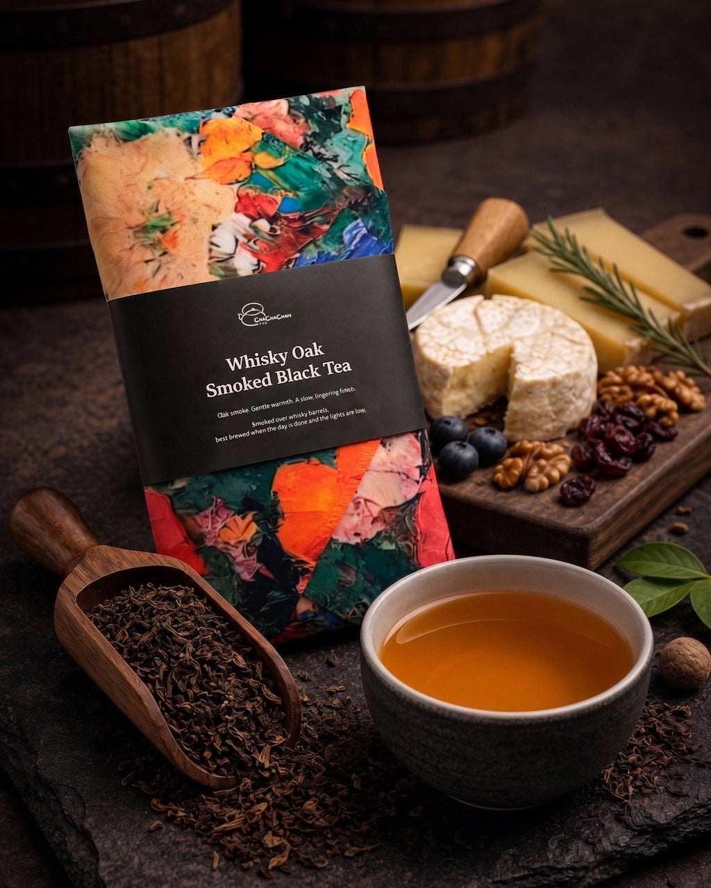 A packaged loose leaf tea from Cha Cha Chan, featuring a colourful abstract paint-stroke pattern in orange, green, red, and cream, wrapped with a black paper band labelled 'Whisky Oak Smoked Black Tea'.